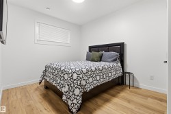 Bedroom featuring wood-finish flooring, white walls, and a window with blinds - 