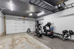 Spacious garage featuring a white overhead door, epoxy floor coating, recessed lighting, and overhead metal storage racks - 
