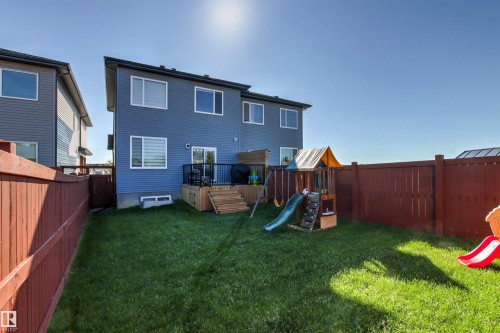 Spacious fenced backyard featuring a substantial wooden deck with stairs, a vibrant green lawn, and full privacy fencing - 7 Tenor Link, Spruce Grove, AB 
