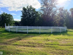 Circular white post and rail fence enclosing a grass-covered area - 