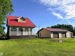 Residential property featuring a red metal roof, dormer window, and a full-width front porch with white railings - 