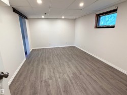 Spacious room featuring wood-finish flooring, white baseboards, and neutral wall paint - 