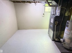 Basement utility area featuring a water heater, furnace, exposed ceiling joists, and a single window - 
