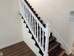 Staircase featuring dark wood treads with patterned runners, white balusters, and a matching newel post - 