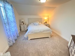 Plush gray carpeting throughout, featuring sloped ceilings and ample wall space - 