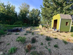 Expansive outdoor space featuring a gravel ground cover and a green storage shed with a shingled roof - 