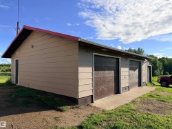 Detached garage building featuring a red metal roof and beige siding - 