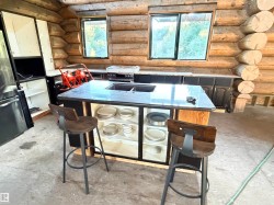 Log cabin interior featuring a central island with a dark stone countertop and integrated sink - 