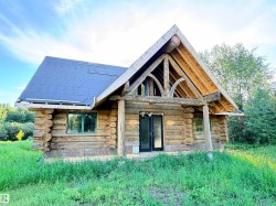Log cabin structure with a dark roofline, exposed wooden rafter tails, and a covered entry - 