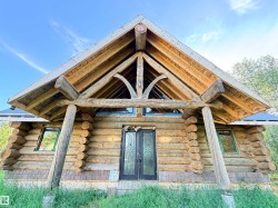 Log cabin exterior featuring a prominent gable roof with exposed timber framing, full-log construction, and decorative shingle siding - 