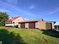Property featuring a two-story residence with a red metal roof and a multi-car garage with brown roll-up doors - 