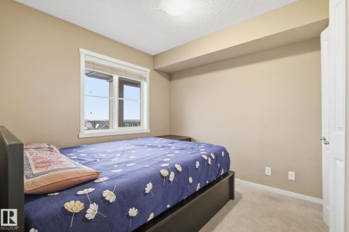 Room featuring a window with white trim, beige wall paint, light-colored carpet, and a white interior door - 424 1510 Watt Drive, Edmonton, AB 