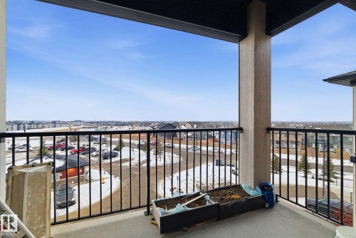 Spacious balcony featuring a black metal railing, textured support column, and concrete flooring - 424 1510 Watt Drive, Edmonton, AB 