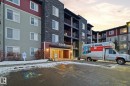 Multi-story residential building featuring a stone facade and red and green siding - 424 1510 Watt Drive, Edmonton, AB 