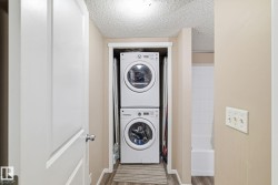 Dedicated laundry alcove featuring a stacked washer and dryer unit, wood-finish flooring, and light neutral wall tones - 