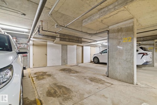 Underground parking garage featuring concrete flooring, exposed ceiling piping, and fluorescent lighting - 424 1510 Watt Drive, Edmonton, AB 