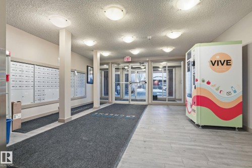 Lobby area featuring light wood-finish flooring and a series of flush-mount ceiling lights - 424 1510 Watt Drive, Edmonton, AB 