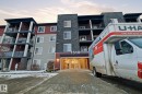 Multi-story building featuring a stone facade, multiple balconies with dark railings, a prominent main entrance, and diverse exterior siding colors - 424 1510 Watt Drive, Edmonton, AB 