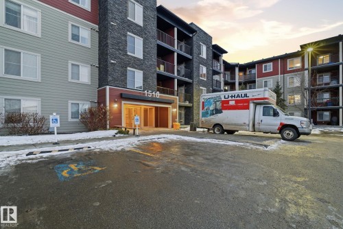 Multi-story building featuring a blend of siding and stone exterior finishes, private balconies, and an illuminated main entrance with double doors - 424 1510 Watt Drive, Edmonton, AB 