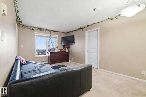 Carpeted room featuring a large window, a ceiling-mounted light fixture, and a white interior door - 424 1510 Watt Drive, Edmonton, AB 