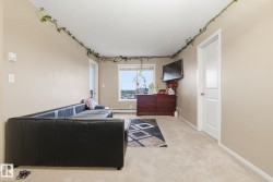 Carpeted room featuring a window with a cityscape backdrop, a built-in wall-mounted television, and a white interior door - 