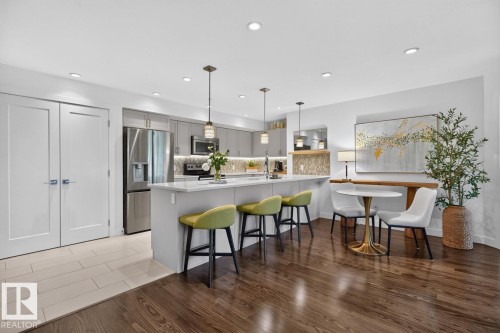 Modern kitchen featuring a large island with seating, stainless steel appliances, and contemporary cabinetry - 207 5025 Edgemont Boulevard, Edmonton, AB 