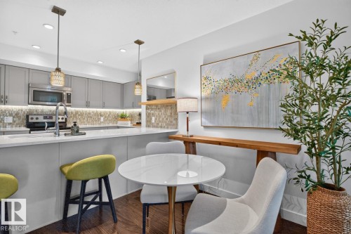 Modern kitchen featuring gray cabinetry, stainless steel appliances, a mosaic tile backsplash, and light-toned countertops - 207 5025 Edgemont Boulevard, Edmonton, AB 