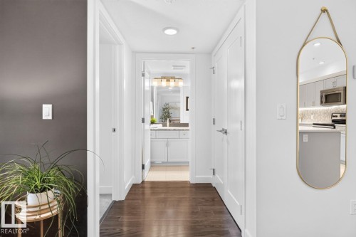 Hallway with wood-finish flooring, white doors, and recessed lighting - 207 5025 Edgemont Boulevard, Edmonton, AB 