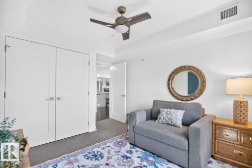 Double-door closet with polished chrome hardware, ceiling fan with integrated lighting, and carpet flooring - 207 5025 Edgemont Boulevard, Edmonton, AB 