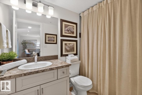 Bathroom featuring a vanity with an integrated sink, laminate countertop, and mosaic tile backsplash - 207 5025 Edgemont Boulevard, Edmonton, AB 