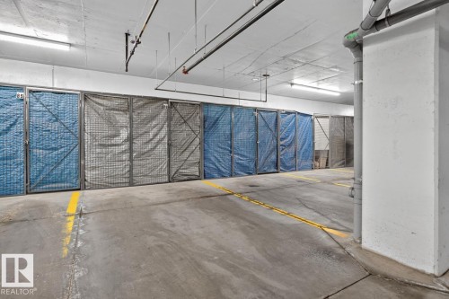 Concrete flooring with yellow demarcation lines, featuring a row of secured storage units - 207 5025 Edgemont Boulevard, Edmonton, AB 