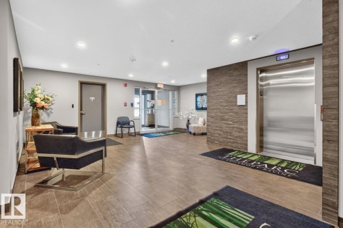 Lobby area featuring wood-finish tile flooring, recessed lighting, and a stainless steel elevator - 207 5025 Edgemont Boulevard, Edmonton, AB 