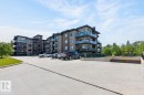 Contemporary apartment building featuring a multi-story facade with balconies, glass railings, dark-framed windows, and an underground parking entrance - 207 5025 Edgemont Boulevard, Edmonton, AB 
