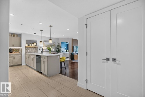 Kitchen island featuring a single-basin sink, pendant lighting, and integrated dishwasher - 207 5025 Edgemont Boulevard, Edmonton, AB 