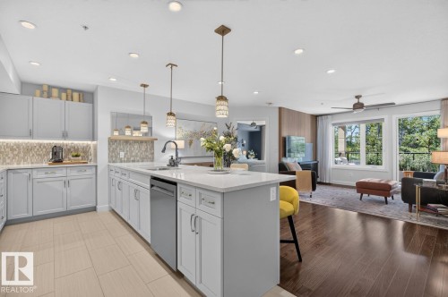 Spacious kitchen featuring an extended island with a built-in sink and dishwasher, light-toned cabinetry, and recessed lighting - 207 5025 Edgemont Boulevard, Edmonton, AB 