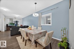 Open concept dining space featuring a contemporary pendant light fixture, wood-finish flooring, and a large window with blinds - 