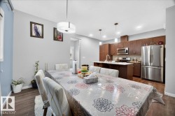 Open-concept kitchen and dining area featuring wood-finish flooring, recessed lighting, and a contemporary pendant light fixture - 