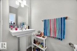 Modern pedestal sink with chrome faucet, large vanity mirror, and contemporary overhead lighting - 