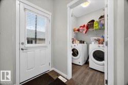 Laundry area featuring a front-loading washer and dryer, wire shelving, and wood-finish flooring - 