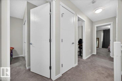 Hallway featuring contemporary white doors with horizontal detailing, neutral gray wall paint, and gray carpet flooring - 1187 Cy Becker Road, Edmonton, AB 