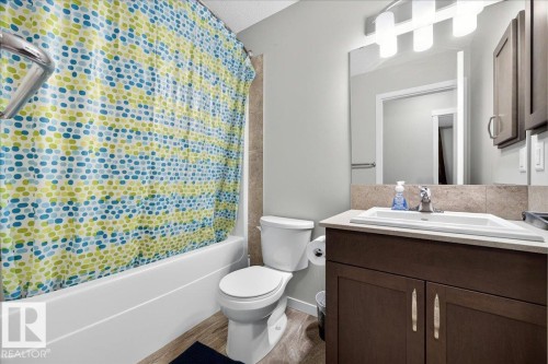 Bathroom featuring a full-size bathtub, wood-finish flooring, a contemporary vanity with an undermount sink, a large mirror, and overhead vanity lighting - 1187 Cy Becker Road, Edmonton, AB 