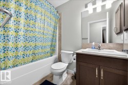 Bathroom featuring a full-size bathtub, wood-finish flooring, a contemporary vanity with an undermount sink, a large mirror, and overhead vanity lighting - 