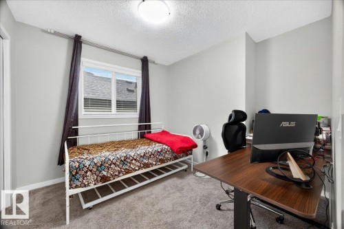 Bright room featuring neutral wall paint, a double window with horizontal blinds and dark drapery, and textured carpeting - 1187 Cy Becker Road, Edmonton, AB 