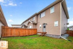 Fenced backyard featuring a wooden privacy fence, a partial deck, and a grass lawn - 