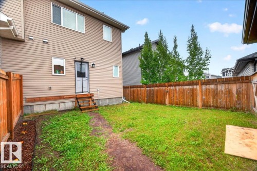 Rear exterior featuring tan horizontal siding and multiple windows - 1187 Cy Becker Road, Edmonton, AB 