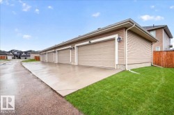 Row of four single-car garages with beige panel doors, light-colored siding, and individual exterior lighting fixtures - 