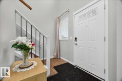 Entryway featuring a paneled door with transom window, wood-finish flooring, and a staircase with white newel posts and dark metal balusters - 