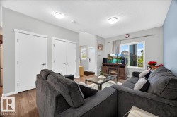 Open-concept living area featuring wood-finish flooring, recessed lighting, and a prominent window - 