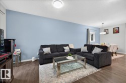 Open-concept living area featuring wood-finish flooring, light blue wall finishes, and a contemporary ceiling light fixture - 