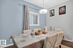 Dining area featuring wood-finish flooring, a contemporary drum pendant light, and a window with horizontal blinds and drapery - 